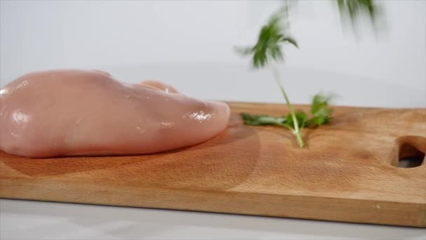 Bouquet de persil tombe sur la planche à découper près du filet de poulet — Video