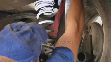 Araba parçaları bir araba altında çalışırken teftiş makinist