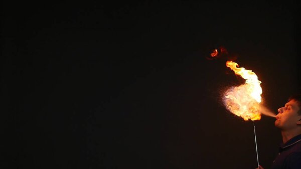 Fire show performance. A man picks gasoline at a torch, slow motion