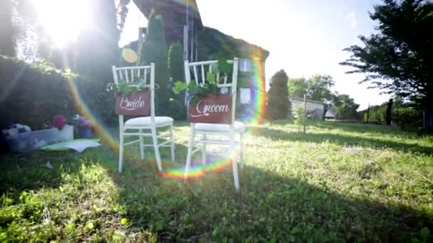 Sillas en una boda. Decorado con Firmas. Lugar para una ceremonia de boda con las luces de un sol — Vídeos de Stock