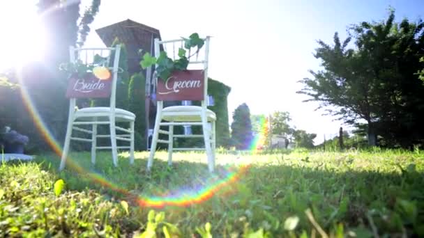 Stühle bei einer Hochzeit. Mit Unterschriften verziert. Ort für eine Hochzeitszeremonie im Licht der Sonne — Stockvideo