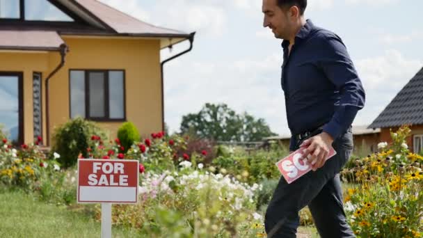 Realtor βάζει πινακίδα ΠΟΥΛΗΘΗΚΕ στην πινακίδα προς πώληση μπροστά από το σπίτι — Αρχείο Βίντεο