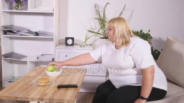 Hamburger yemek ve televizyon izlerken şişman kadın