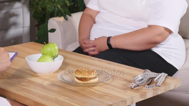 Товста жінка вибирає між яблуком і бургер. Дієта і здоровий — стокове відео