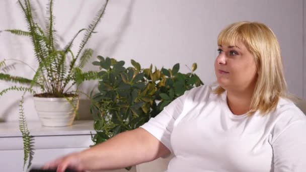 Overgewicht blonde vrouw zittend op de Bank Tv-kijken — Stockvideo
