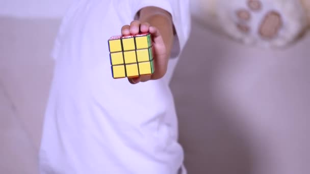 Çocuk rubik küp toplar ve kameraya gösterir — Stok video