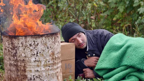 En hemlös man som sover nära elden — Stockfoto