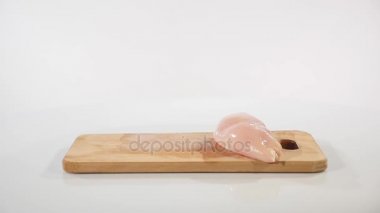 çiğ tavuk fileto parçalarını bir ahşap tahta üzerine düşüyor