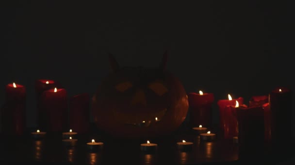 Esculpido Halloween abóbora luzes dentro com chama em um fundo preto com velas acesas de perto — Vídeo de Stock