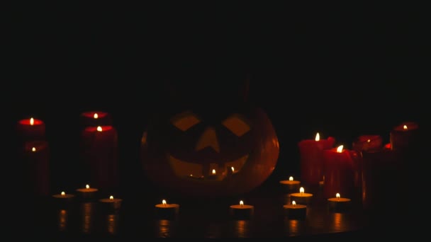 Lumières sculptées de citrouille d'Halloween à l'intérieur avec la flamme sur un fond noir avec des bougies allumées fermer — Video