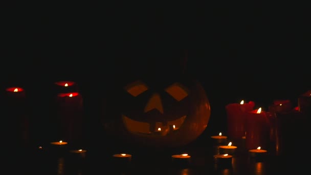 Різьблений гарбуз Хеллоуїн світиться всередині з полум'ям на чорному тлі з освітленими свічками крупним планом — стокове відео