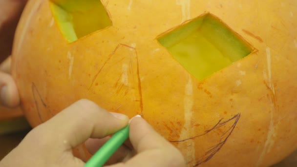 Pan of a boy drawing the Jack-o-lantern face on his halloween Pumpkin — Stock Video