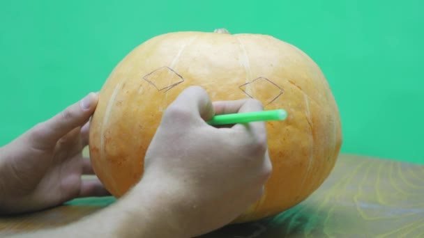 Пан мальчик рисует лицо Джека-фонаря на своей Хэллоуинской тыкве — стоковое видео
