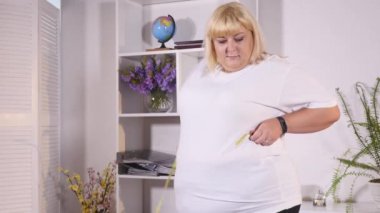 şişman kadın bel ölçer ve hamburger yiyor