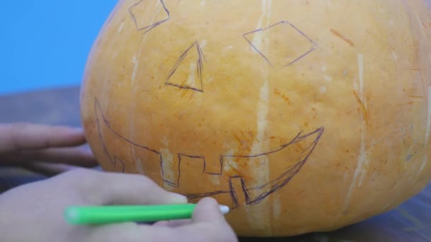Pan chłopca, rysunek twarz Jack-o-lantern na jego halloween dynia — Wideo stockowe