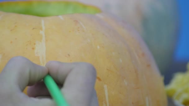 Pan d'un garçon dessinant le visage Jack-o-lanterne sur sa citrouille d'Halloween — Video