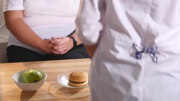 Ernährungsberaterin schenkt einem Kunden Äpfel und Burger — Stockvideo