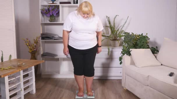 Толстая женщина стоит на весах и показывает класс — стоковое видео