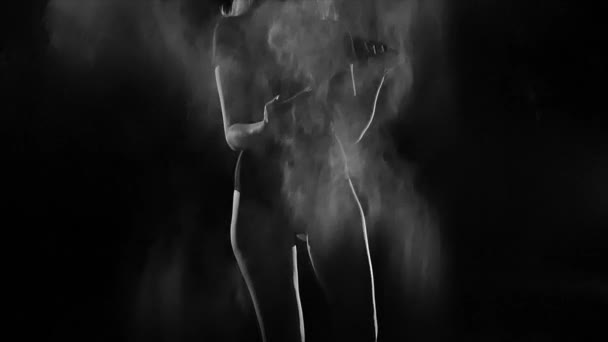 Jonge vrouw in een witte lege wolk van meel in een zwarte achtergrond — Stockvideo