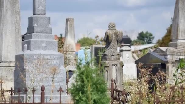 Каменный крест на старом кладбище. Тёмно-готическое кладбище. Облака над заброшенным кладбищем. Старые могилы во время первой мировой войны. Церковь среди заросших могил — стоковое видео