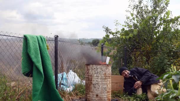 Een dakloze man slapen in de buurt van het vuur — Stockvideo