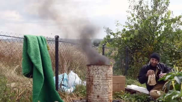 貧しい人々 の近く温暖化火災ゴミ バレルと飲み物ウォッカ — ストック動画