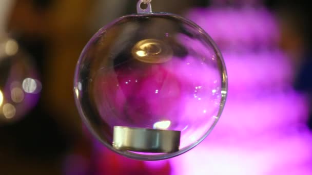 Стеклянные шарики со свечами висят перед окном — стоковое видео