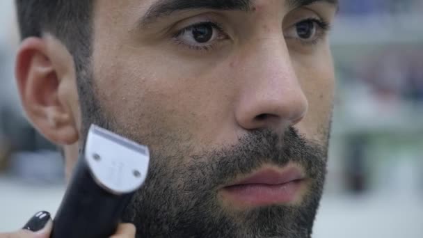 Processus de coiffure. Gros plan d'un coiffeur séchant les cheveux d'un jeune homme barbu — Video