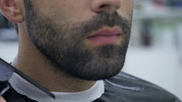 Hairstyling process. Close-up of a barber drying hair of a young bearded man — Stock Video