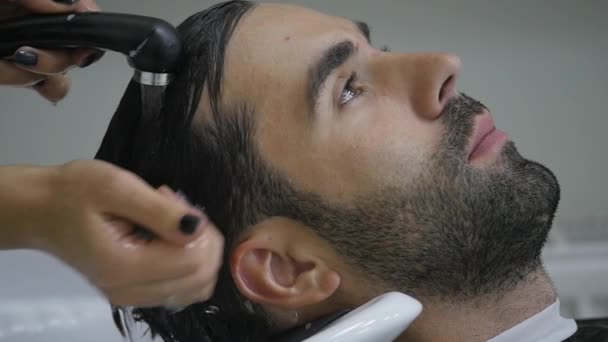 Primer plano de un joven lavándose el pelo en un salón de peluquería — Vídeo de stock