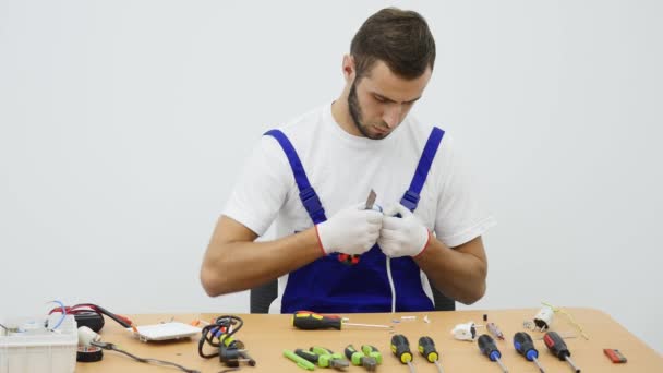 Serviceman in blue work suit sits for the work table — Stock Video