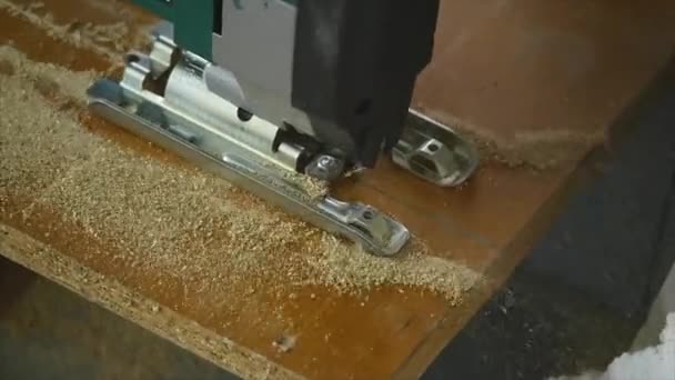 Gros plan d'un menuisier découpant une planche de bois. Un homme coupe un morceau de bois avec une scie circulaire tenue à la main 