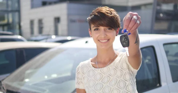 Młoda kobieta trzyma klucze do nowych samochodów auto i uśmiecha się do kamery — Zdjęcie stockowe