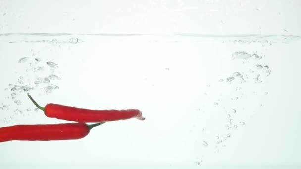Closeup verse pepers te laten vallen in water — Stockvideo