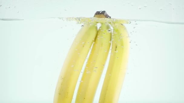 Bananen stürzen in Zeitlupe auf weißem Hintergrund ins Wasser — Stockvideo