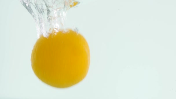 Slo-motion whole orange falling into water — Stock Video