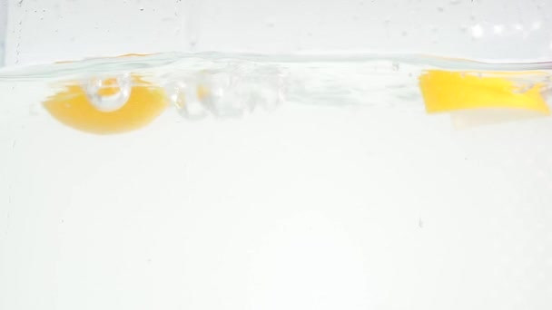 Suya düşen ve portakal dilimleri üzerinde beyaz arka plan yavaş düşüyor — Stok video
