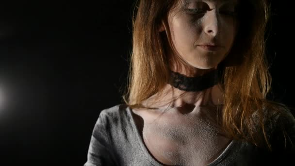 Une belle jeune fille pose dans un studio devant un fond noir.Comme elle pose de grandes quantités de farine blanche tombent sur son corps comme s'il s'agissait de chutes de neige 