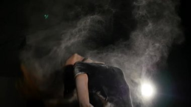 Güzel bir genç kız aşağı diz çöker ve beyaz un ile iscovered. O aniden arkasından throwsher saç ve büyük bir powderexplosion oluşturur