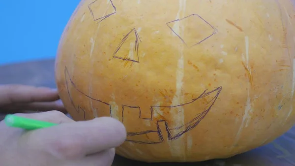 Pan of a boy drawing the Jack-o-lantern face on his halloween Pumpkin — Stock Photo, Image