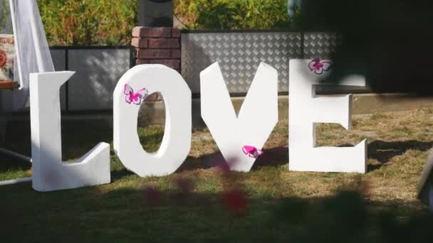 Love word outdoors. Big white plastic letters wedding decoration — Stock Video