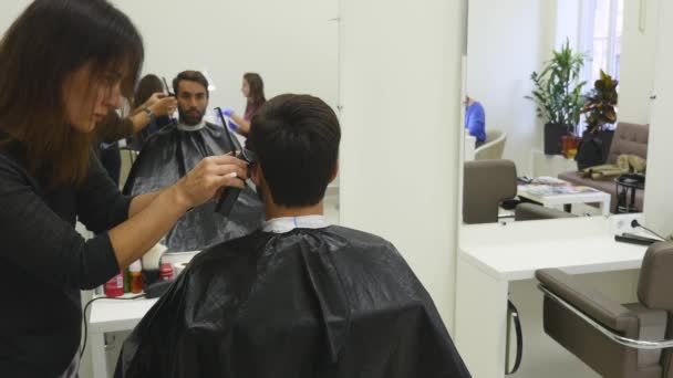 Jeune homme dans le salon de coiffure. Barbier femme et sa cliente . — Video