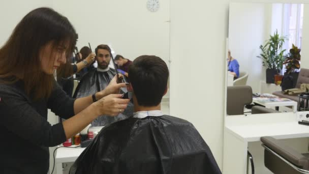 Junger Mann im Friseursalon. Friseurin und ihr Kunde. — Stockvideo