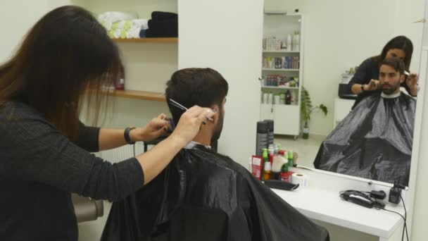 Junger Mann im Friseursalon. Friseurin und ihr Kunde. — Stockvideo