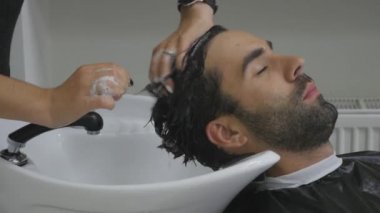 El Kuaför müşteri saç için su dökün. İstemcinin saç kesme berber sonra yıkar. Yakın çekim. 4k