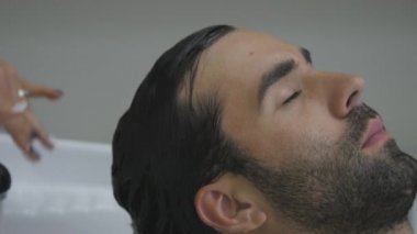 El Kuaför müşteri saç için su dökün. İstemcinin saç kesme berber sonra yıkar. Yakın çekim. 4k