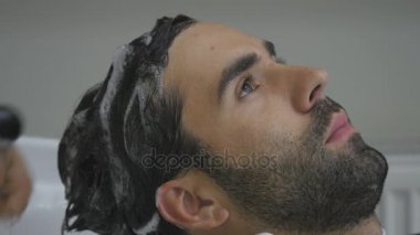 El Kuaför müşteri saç için su dökün. İstemcinin saç kesme berber sonra yıkar. Yakın çekim. 4k