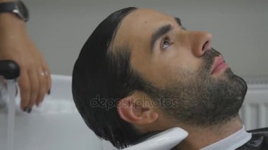 El Kuaför müşteri saç için su dökün. İstemcinin saç kesme berber sonra yıkar. Yakın çekim. 4k