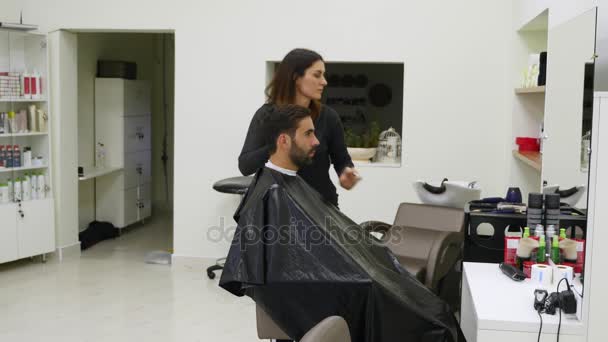 Peluqueros femeninos y masculinos están trabajando con clientes con capas de corte en la barbería — Vídeos de Stock