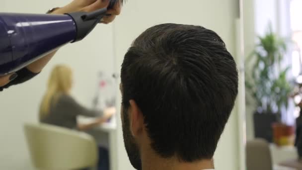 Coiffeur professionnel séchant les cheveux dans un salon de beauté. Homme jeune client et femme coiffeuse. gros plan — Video